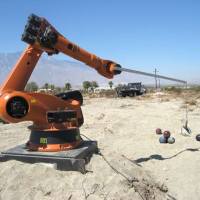 Industrial robot arm catapults flaming bowling balls