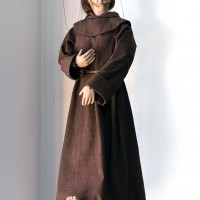 a complex marionette with detailed face and hands dressed in a brown monk's robe