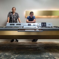 author standing behind large table-sized audio console of knobs and switches
