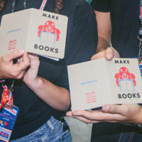 Two pairs of hands hold two books that both say "Make Books" on the cover.